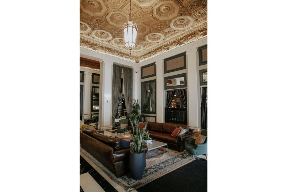 A sophisticated and welcoming lounge with leather sofas, elegant lighting, potted plants, and a decorative rug. The space is designed for relaxation, social gatherings, and comfortable conversations, echoing hotel-style comforts.